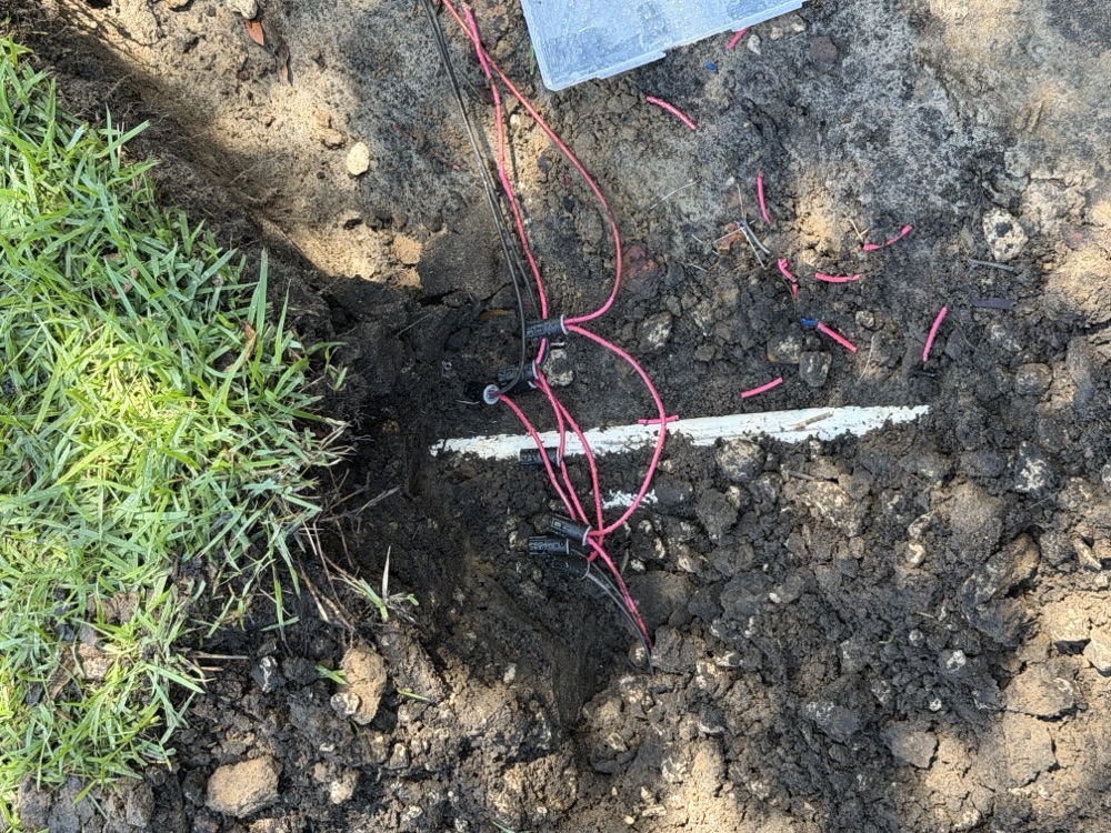 Irrigation valve wiring spliced with waterproof connectors in an open trench